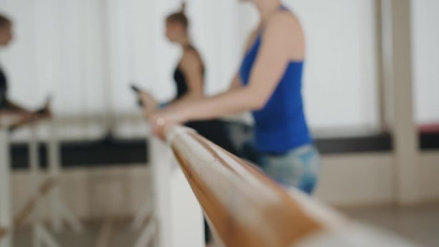 Two girls in gym clothes stretches the muscles of the legs on the crossbar.
