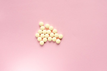 Yellow pills on a pale pink background