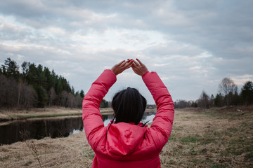  girl in a pink winter jacket does exercises on nature in Russia near the river