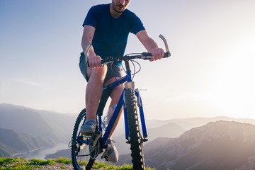 Fototapeta premium Close up photo from a mountain biker riding his bike ( bicycle) on rough rocky terrain on top of a mountain, wearing no safety equipment. Adrenalin junkie.
