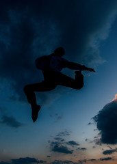 Fototapeta na wymiar A jumping silhouette man on the sunset background