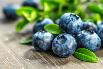 Fresh whortleberry with a green leaf on old wood background.Healthy eating and nutrition.