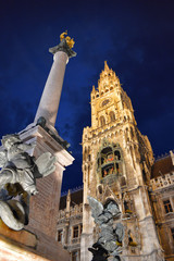 Night low angle view of Town Hall tower, column and sculptures, Munich, Germany