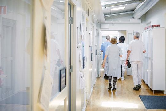 Rear view of doctors and nurses walking in corridor at hospital