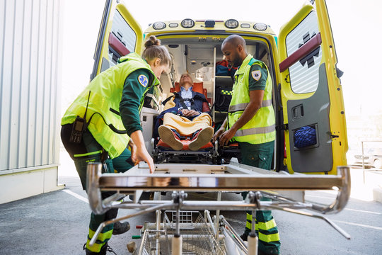 Healthcare workers pulling mature patient from ambulance on hospital gurney