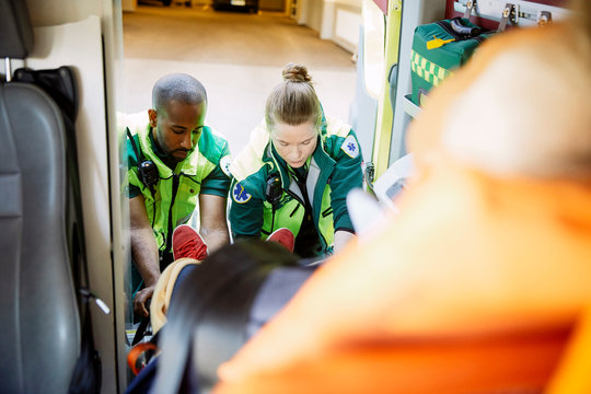 High angle view of rescue team pulling out patient from ambulance