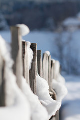 Closeup of Wooden Fence covered in Snow with out of focus Background. Bokeh Background and Snow in the foreground,
