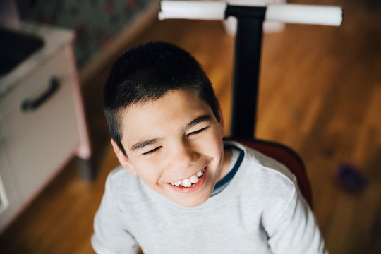 High angle view of happy disabled boy looking away while sitting on wheelchair at home