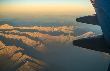 Mountain range seen from Airplane, with plane wing seen on the right side. Mountains during...