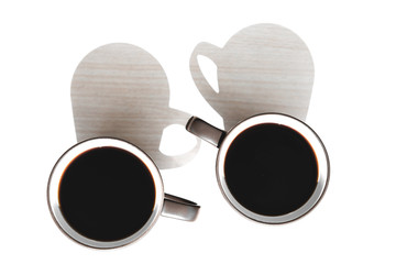 two large dark circles with light walls inside and dark brewed coffee standing on a light table in direct sunlight and casting a shadow