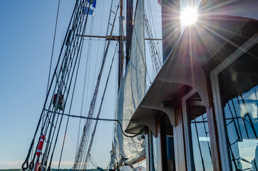 Sunburst next to a mast and sails on a tall ship. © GrB