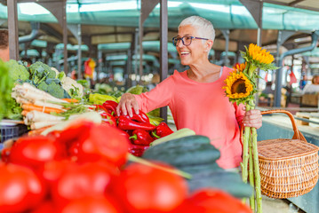 Senior woman shopping on the market healthy vegetables and fruits. Woman buying red peppers at the...