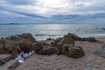 Fototapeta na wymiar Trash hided under a stone at the beach near sea. concept on no plastic and global diseases