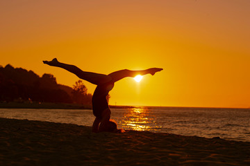 Woman doing yoga on the beach during the sunset in Utthita position, calm and serenity