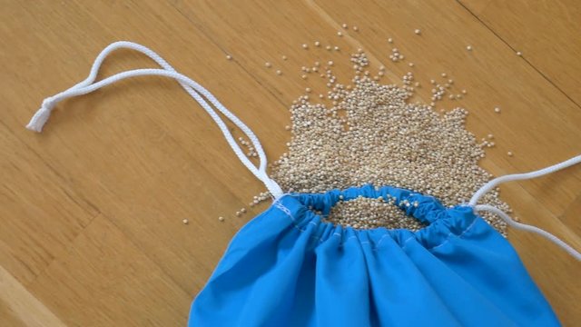 Top view of white quinoa seeds in blue reusable package on wooden background. Healthy eating concept