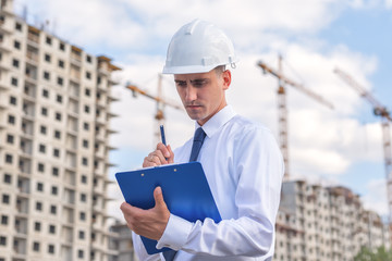 civil engineer in a white helmet makes pencil marks in the documentation.