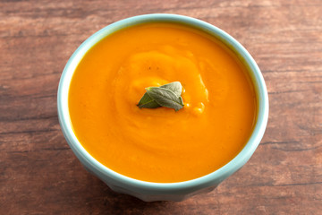 Bowl of Healthy Sweet Potato and Sage Soup on a Rustic Wooden Table