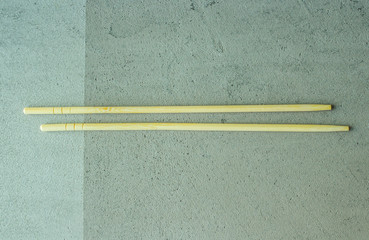 wooden chopsticks sushi rolls on a gray concrete background