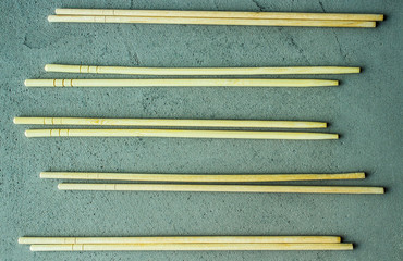 wooden chopsticks sushi rolls on a gray concrete background