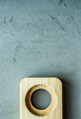 wooden stand with one hole in the middle at the bottom on a gray concrete background