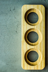 wooden stand with three round symmetric holes on the right side on a gray concrete background