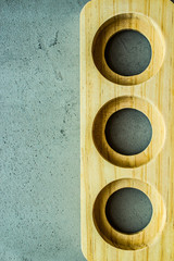 wooden stand with three round symmetric holes on the right side on a gray concrete background