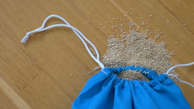 Top view of white quinoa seeds in blue reusable package on wooden background. Healthy eating concept