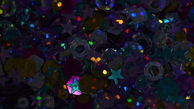 Closeup view of beautiful colorful shiny and sparkling glitter decor glowing in darkness. Real time 4k video footage.