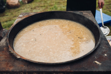 Closeup of delicious soup with potatos and carrots. Selective focus of spoon with tasty healthy dinner during picnic. Concept of cooking, food and cuisine.
