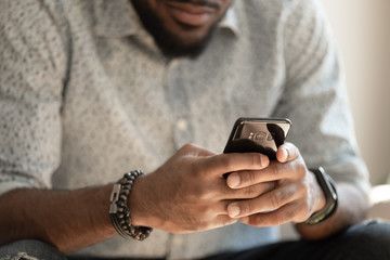 Close up young african american man holding smartphone.