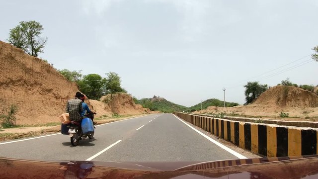 Moving car pov, overtaking a scooter in India