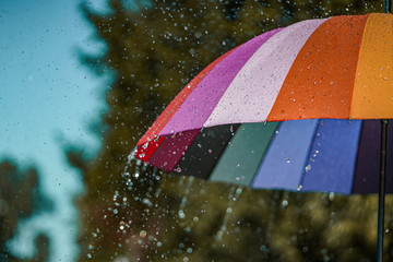 Bright colored rainbow umbrella in the rain weather