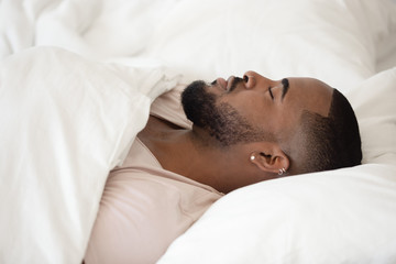 Close up young black man sleeping in bed.