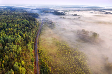 Single track railway through the misty woodland aerial view