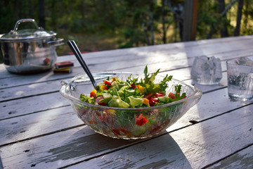 Fresh salad on a wooden table near a forest