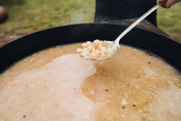 Closeup of delicious soup with potatos and carrots. Selective focus of spoon with tasty healthy dinner during picnic. Concept of cooking, food and cuisine.