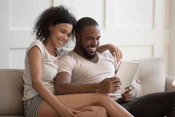 Obraz premium Smiling african american couple using tablet together.