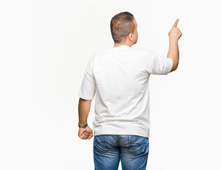 Middle age arab man wearig white t-shirt over isolated background Posing backwards pointing behind with finger hand