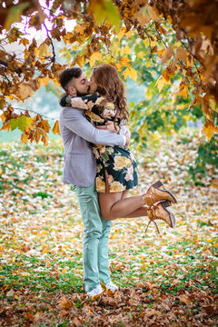 Outdoors photo, beautiful, young couple kissing under the yellow oak tree.