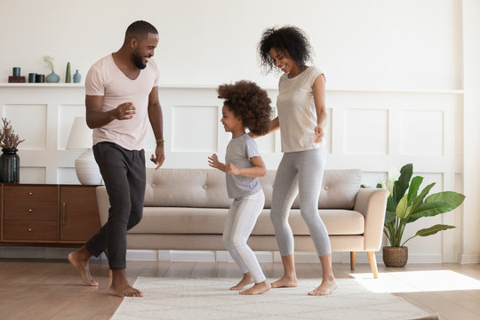 Happy african american family having fun, dancing at home.
