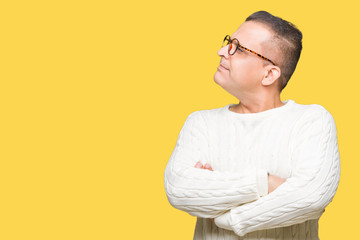 Middle age arab man wearing glasses over isolated background smiling looking to the side with arms...