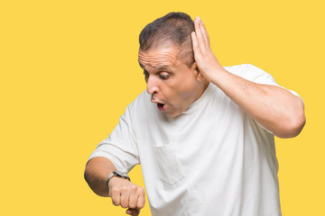 Middle age arab man wearig white t-shirt over isolated background Looking at the watch time...