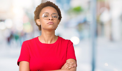 Beautiful young african american woman wearing glasses over isolated background skeptic and...