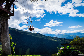 Woman on the swing of the end of the world (Columpio del fin del mundo) in Baños, Ambato. The tree...