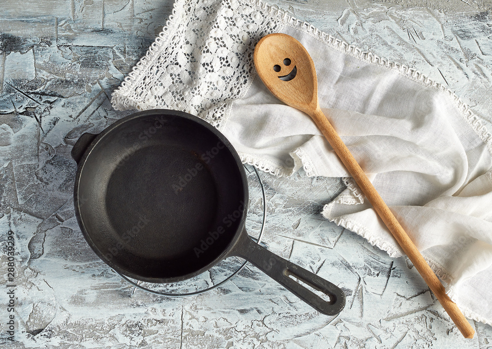 Poster empty black round frying pan with handle and spoon