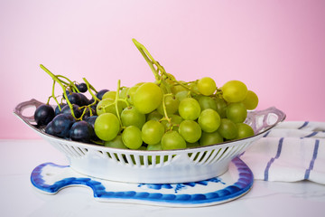 Black grapes and green grapes on a white table