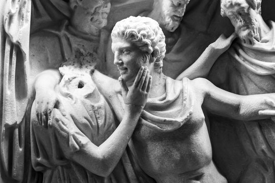 Black and white photo of marble sculptures showing a man hugging a headless female statue