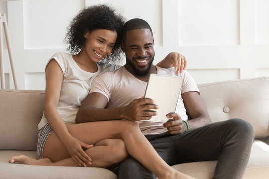 Smiling happy african american family spouse using digital tablet.