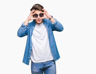 Young handsome man wearing sunglasses over isolated background Trying to open eyes with fingers, sleepy and tired for morning fatigue