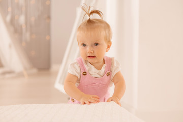 Fototapeta premium baby girl in the nursery playing,bright children's room, textiles for children's room